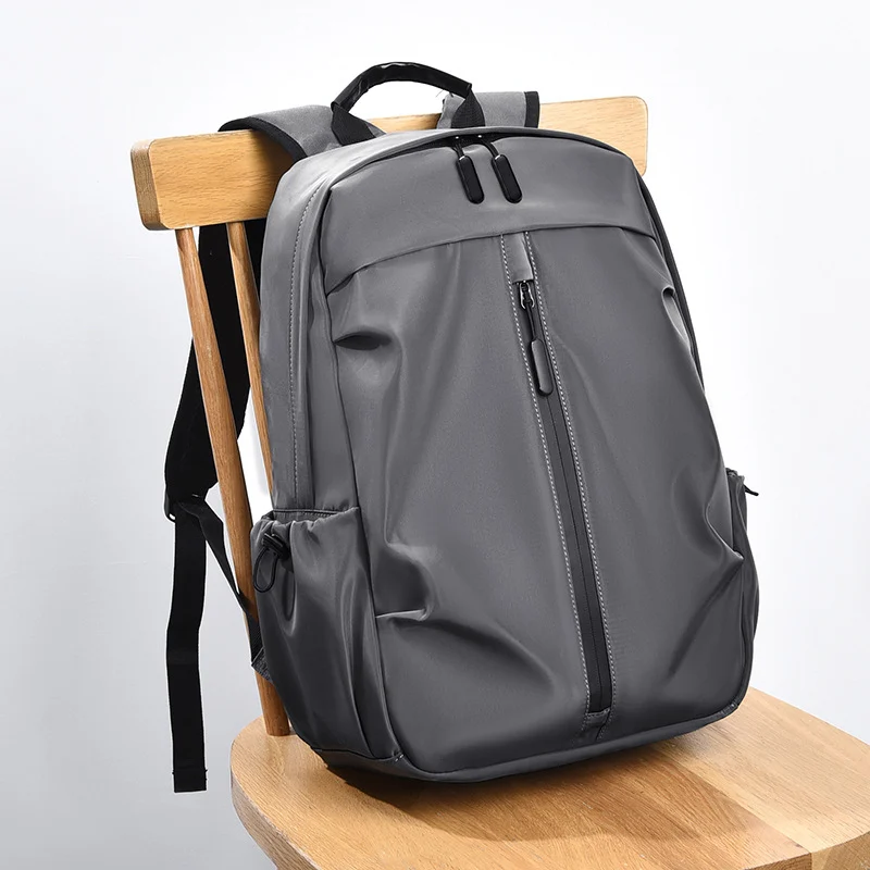 Grey vertical-zip backpack with a vertical front zip and top handle