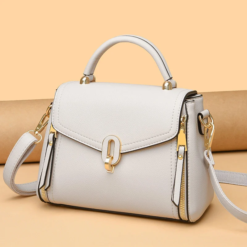 Cream smooth leather flap bag with an oval gold clasp and arched top handle