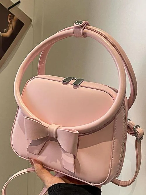 Pink bag with a bow on the front and a looped top handle