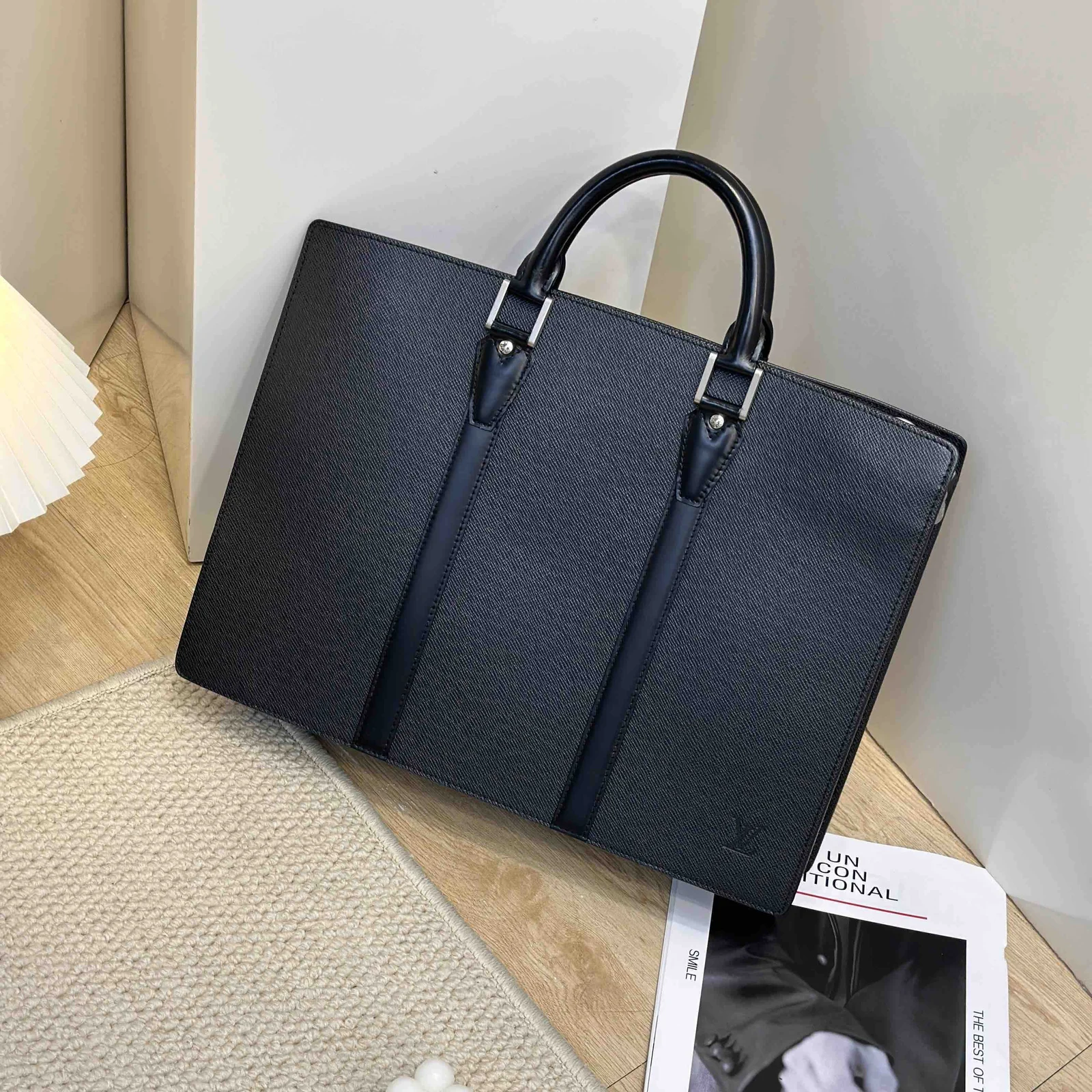 Black textured leather briefcase with two top handles and silver strap tabs