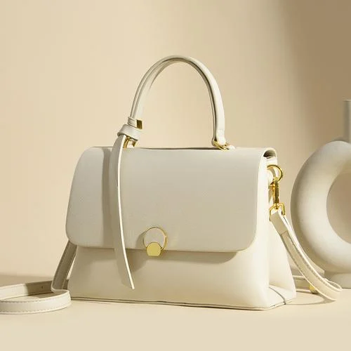 Cream flap bag with a circular gold lock and a leather tassel on the handle